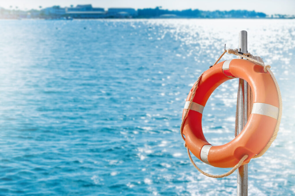 lifebuoy circle. scenic view of red and white lifebuoy on post on seaside beach. scenery landscape of sea ocean shore on sunny day. water rescue concept.