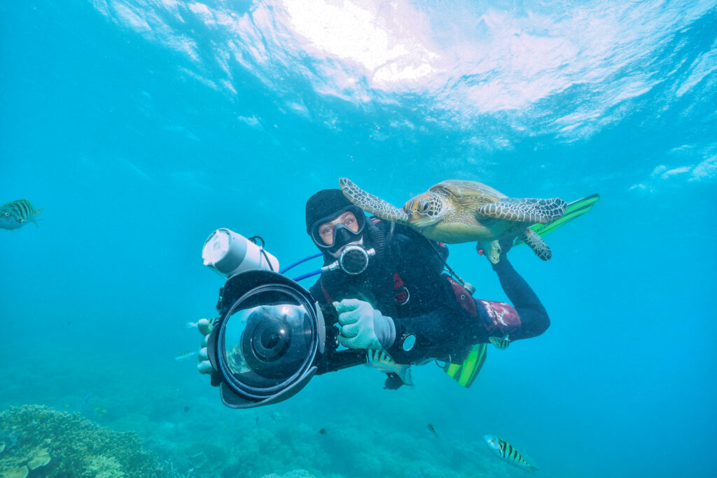 under water photographer diving righ next to turtle
